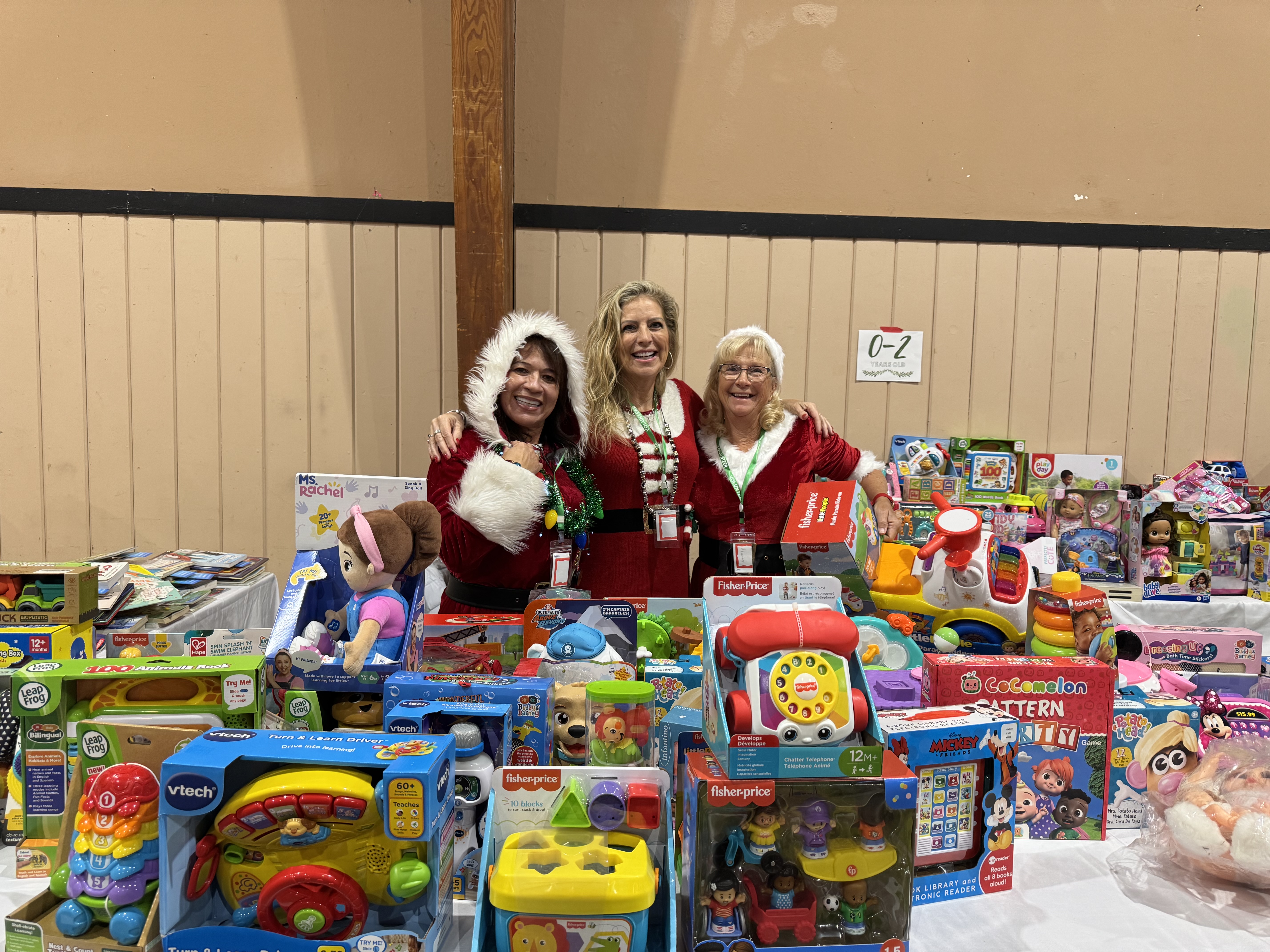 Three Toy Run volunteers standing behind tables filled with donated toys.